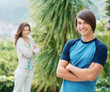 Smiling young guy with girlfriend at the back