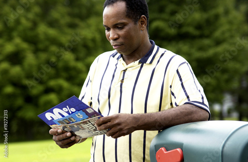 Photo: African American man getting mail from mailbox African American man getting mail from mailbox