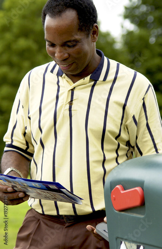 Photo: African American man getting mail from mailbox African American man getting mail from mailbox