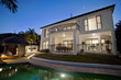 Photo: Luxurious mansion exterior at dusk overlooking pool Luxurious mansion exterior at dusk overlooking pool