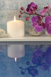 Arrangement mit Kerze, Orchideen und Wasser