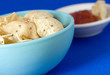 A bowl of white corn tortilla chips with salsa bowl