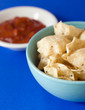 A bowl of white corn tortilla chips with salsa bowl