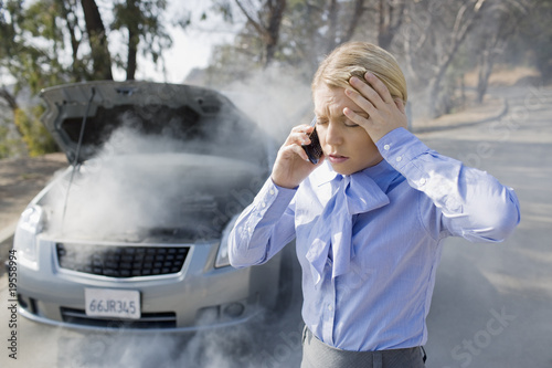 Photo: Frustrated businesswoman calling for help for smoking car Frustrated businesswoman calling for help for smoking car