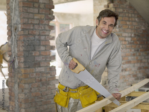 Foto: Man sawing wood at construction site Man sawing wood at construction site
