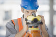 Surveyor in hard-hat using surveying equipment