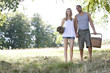 A young couple holding hands, carrying a picnic basket