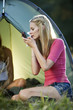 Two young women camping, one wiping her face