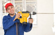 A young handyman holding in his hand a big drill