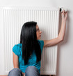 Frau mit Heizkörper und Thermostat einer Heizung