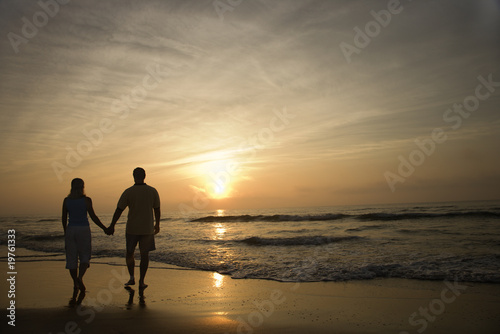 Photo: Couple Walking on Beach at Sunset Couple Walking on Beach at Sunset