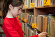 Young girl looking for books in library