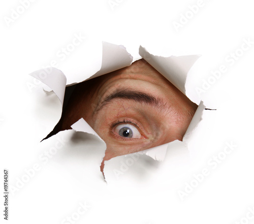 Foto: Auge starrt durch Papierloch Auge starrt durch Papierloch