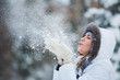 Beautiful woman blowing in the snow