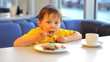 Little funny boy eat cake in cafe