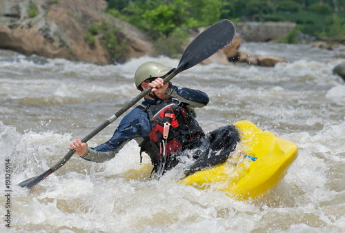 Photo: Kayaker fighting the rapids of a river. Kayaker fighting the rapids of a river.