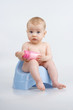 Infant on potty with bottle.
