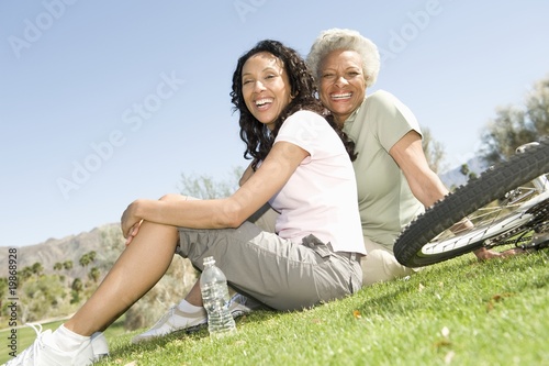 Photo: Mother and daughter sit in park with mountain bikes Mother and daughter sit in park with mountain bikes