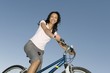 Woman sits on mountain bike against clear blue sky