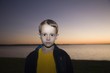 Boy stares at camera from sunset beach