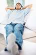 Young guy listening music with headphones , relaxing on couch