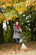 A young woman standing with a rake in autumn time