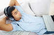 Man relaxing on couch with headphones and laptop at home