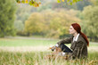 A young woman sitting in the grass, holding a leaf