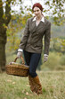 A young woman standing in a field, holding a wicker basket