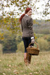 A young woman walking through a field holding a wicker basket