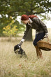 A young woman standing in a field with her dog