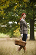 A young woman walking through a field, holding a wicker basket