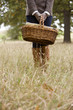 A young woman standing in a field, holding a wicker basket