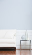 White Sofa and Glass End Table Against Blue Wall