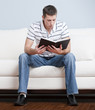 Young Man Sitting on Sofa Reading