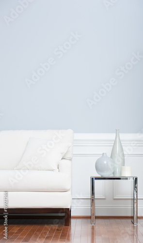 Photo: White Sofa and Glass End Table Against Blue Wall White Sofa and Glass End Table Against Blue Wall