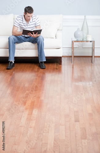Photo: Young Man Sitting on Sofa Reading Young Man Sitting on Sofa Reading
