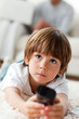 Concentrated little boy watching TV lying on the floor