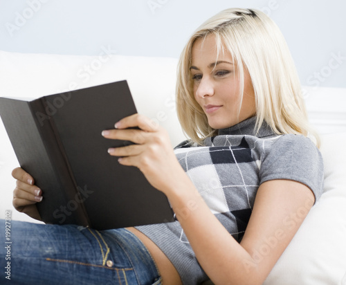 Photo: Young Woman Lying on Sofa Reading Book Young Woman Lying on Sofa Reading Book