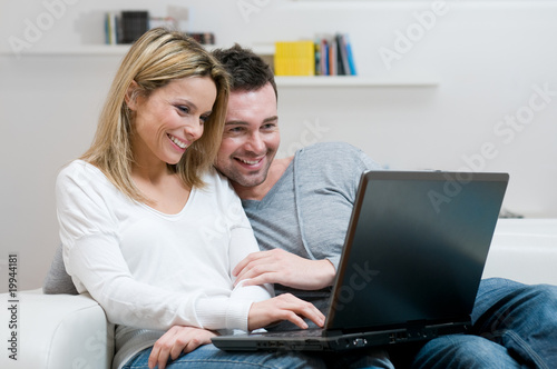 Photo: Smiling young couple with laptop Smiling young couple with laptop