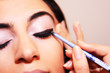Young woman applying makeup on eye with a cosmetic black pencil