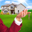 Hand Holding House Keys in Front of Home