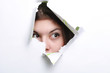 The girl spies through a hole in a paper.