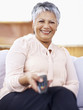 Happy old woman with a television remote control