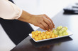 Closeup of a person plucking grapes from a fruit plate