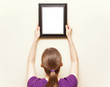 Details der Fotografie Woman hanging a picture on the wall.