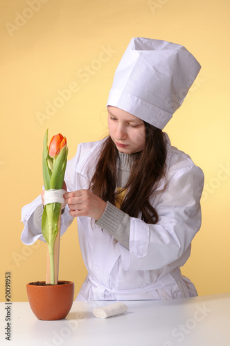 Photo: Preteen girl in nurse uniform taking care on flower Preteen girl in nurse uniform taking care on flower