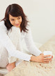 Happy young female drinking coffee while at the kitchen