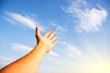 Open hand over blue sky and white clouds
