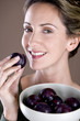 A mid adult woman eating a plum